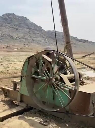 Drilling operation observed in rural Afghanistan, workers rest nearby