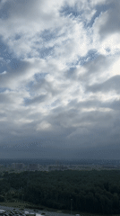 Highway traffic jam beside Kudrovo forest under breaking clouds