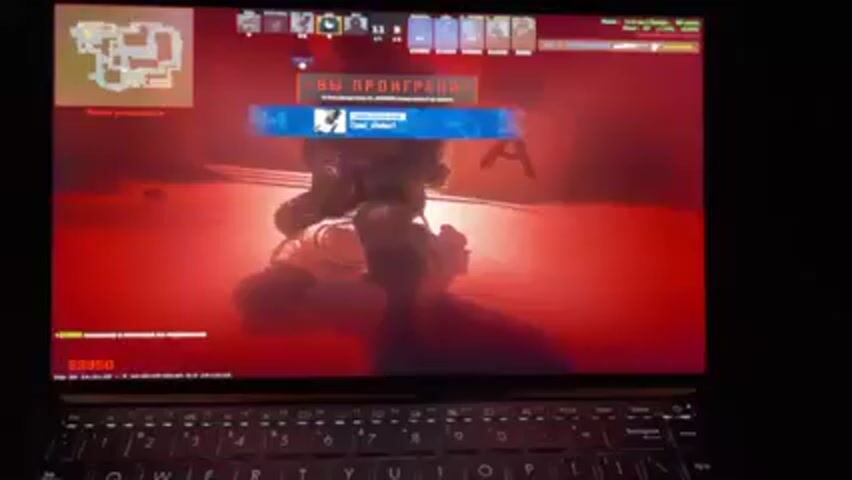 A laptop screen shows gameplay of Counter-Strike: Global Offensive. The text "You lost" is displayed on the screen. Then the screen switches to gameplay from a first-person perspective. The player is standing in a narrow street with buildings on either side, holding a bomb in their hands. Another player can be seen in the distance.
