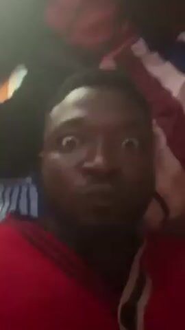 The video shows a close-up of a person's face with wide eyes. The camera then moves upwards, revealing a person wearing a red jacket and a flag with white and blue stripes above the first person. The camera continues to move, and the image becomes blurry.
