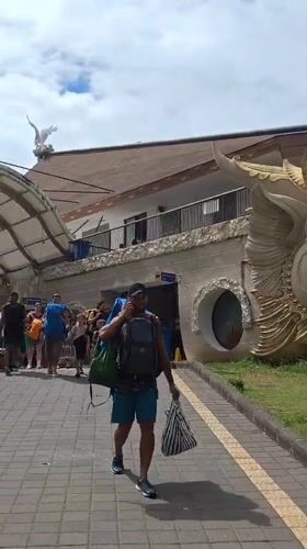 Traveler walks past traditional Balinese demon statue in Denpasar terminal