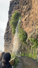 Waterfall flows down cliff onto road in Ponta do Sol