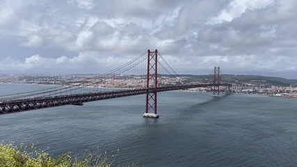 Red suspension bridge filmed under cloudy skies in Almada