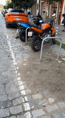 Orange motorcycle parked on cobblestone street in Sofia
