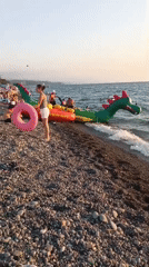 Inflatable dragon boat and sunset on Kobuleti's pebble beach