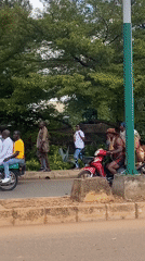 Street procession winds through Bukuru with crowds, horses, and motorcycles