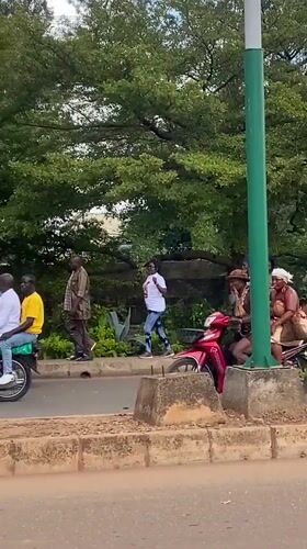 Street procession winds through Bukuru with crowds, horses, and motorcycles