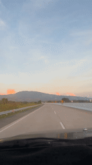 Evening highway travel captured near Indonesian mountains at sunset