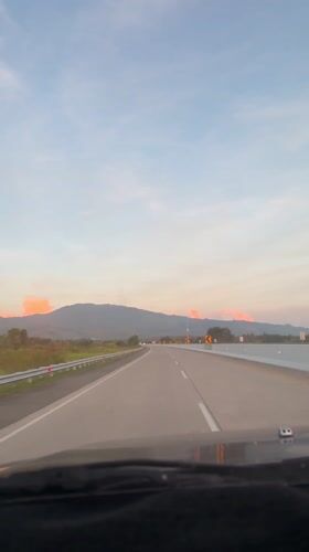 Evening highway travel captured near Indonesian mountains at sunset
