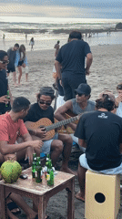 Beach musicians gather for informal guitar session in Kuta