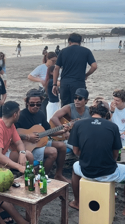Beach musicians gather for informal guitar session in Kuta