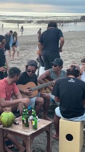 Beach musicians gather for informal guitar session in Kuta