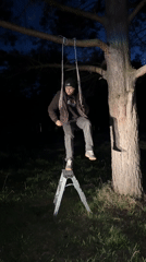 Man stands on stepladder in yard at night