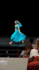 Woman performs dance routine on stage for filming audience