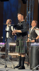Scottish bagpiper performs with drummers on Moscow stage