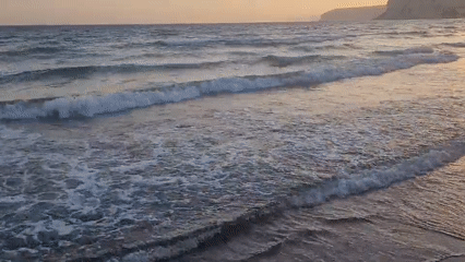 Drone glides along a choppy Cyprus shoreline at sunset