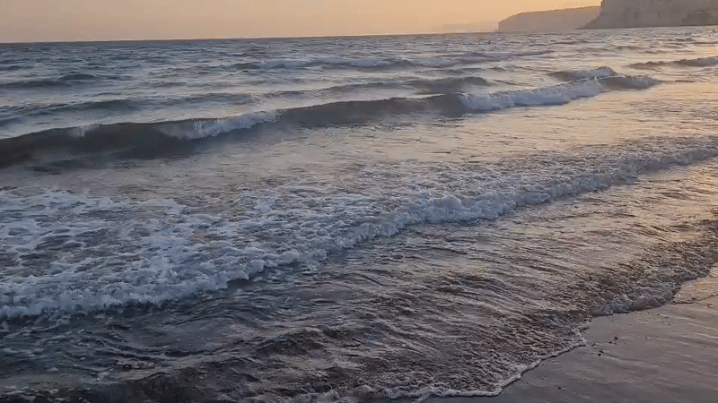 Drone glides along a choppy Cyprus shoreline at sunset