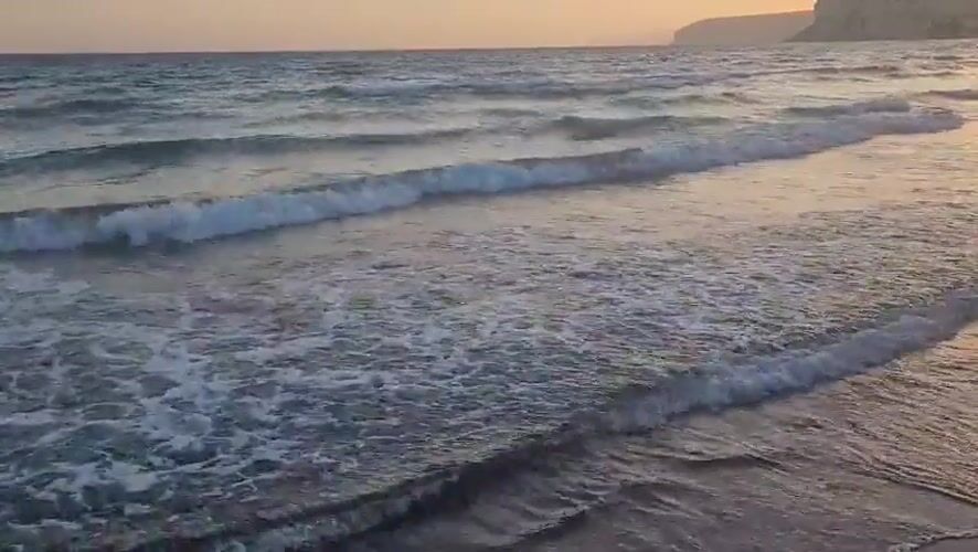 Drone glides along a choppy Cyprus shoreline at sunset