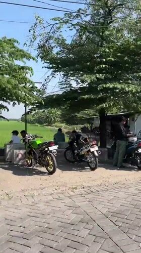 Rural Indonesian village life with motorcycles and rice fields