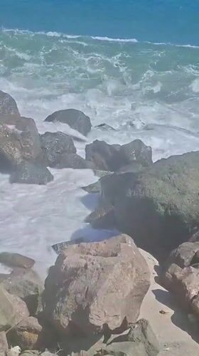 Sunny afternoon on a rocky, resort-backed coastline