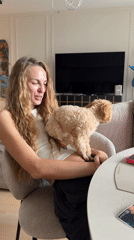Woman holds small poodle in Moscow living room