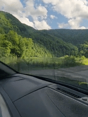 Scenic mountain valley road flanked by water and forest, Ukraine