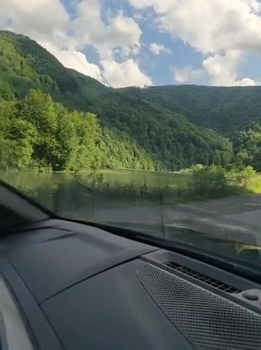 Scenic mountain valley road flanked by water and forest, Ukraine
