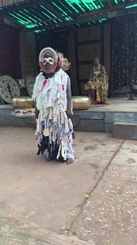 Fire-breathing performer in layered costume entertains audience in Accra