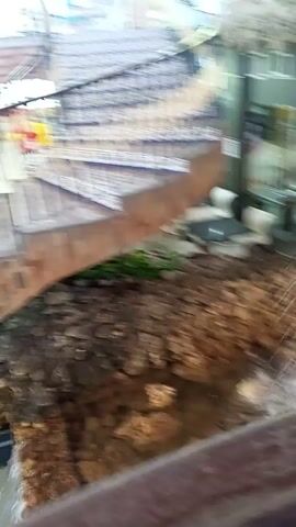 The video shows an interior space with a decorative waterfall feature flowing over rock formations and glass panels. There are dining areas at varying levels that are decorated in the same rock-themed manner. The camera pans up to show more of the waterfall and the restaurant decor.