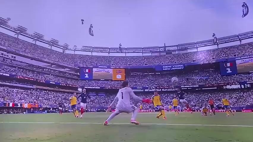 The video begins with a wide shot of a soccer stadium with a soccer game in progress. A goalkeeper is attempting to save a goal. The camera then cuts to a close-up of a textured purple ceiling with hexagonal patterns. The video then shifts to a close-up of a man with white hair wearing a suit and white shirt, sitting on a bench and looking to the left. He is then shown standing up and running, with his arms raised and fists clenched, appearing to be celebrating. Another man with a white shirt is partially visible to his right. The background shows a crowd of people and stadium seating. The video ends with a brief shot of a water cooler with the word "ADE" visible.