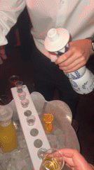 Person fills shot glasses from decorative bottle in Paris
