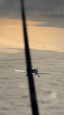 Small planes fly in formation above clouds at golden hour