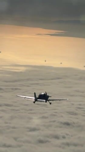 Small planes fly in formation above clouds at golden hour