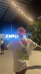 Roller skaters dance near AMPLITUDE sign in outdoor area