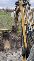 Excavator digs water-filled trench in Bulgarian village construction project