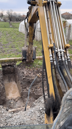 Excavator digs water-filled trench in Bulgarian village construction project