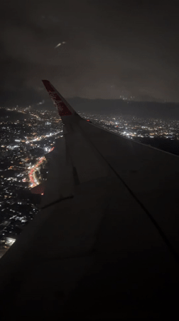 AirAsia flight observed over illuminated Kuta cityscape at night