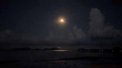 Full moon illuminates Thai coastal waters during nighttime scene