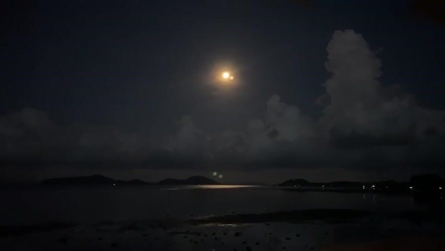 Full moon illuminates Thai coastal waters during nighttime scene