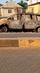 Burned minivan documented on Ikorodu street amid routine daily scenes