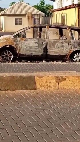 Burned minivan documented on Ikorodu street amid routine daily scenes