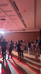 Young people slow dance under spotlights in formal room