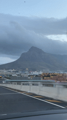 Driver approaches Cape Town under cloudy mountain skies