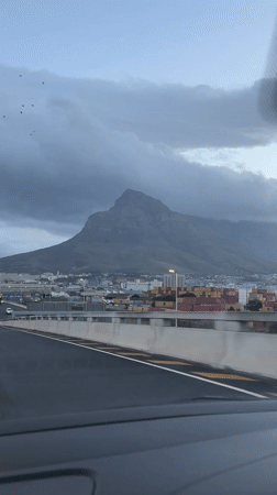 Driver approaches Cape Town under cloudy mountain skies