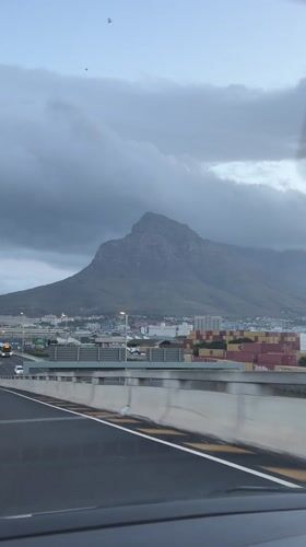 Driver approaches Cape Town under cloudy mountain skies