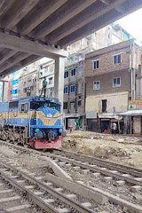 Masked person rides atop slow-moving train in Dhaka