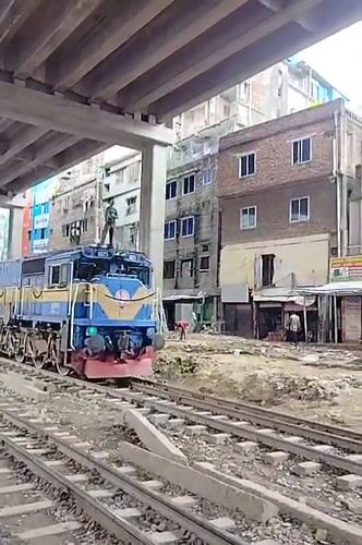 Masked person rides atop slow-moving train in Dhaka