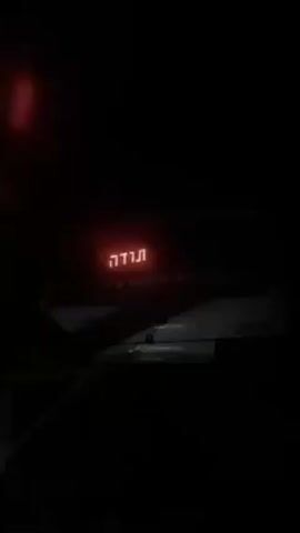 The video shows a partially obscured, white vehicle in a dark setting. The vehicle has Hebrew writing on its back. The camera angle and lighting make it difficult to discern further details.
