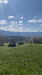 Four ATV riders cross green field near Apriltsi, Bulgaria