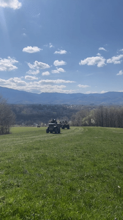 Four ATV riders cross green field near Apriltsi, Bulgaria